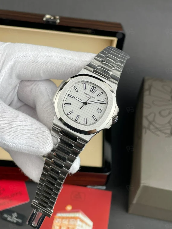 Patek Philippe Nautilus, beyaz yatay çizgili kadranlı, çelik kasalı ve bilezikli, otomatik mekanizmalı, ince kasalı lüks kol saati
