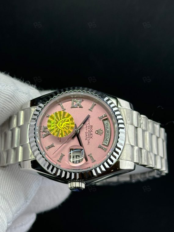 Rolex Day-Date paslanmaz çelik kasa, pembe kadran, President bilezik, yivli bezel ve gün/tarih göstergeli yakın çekim görseli - Erişilebilir klasik lüks saat